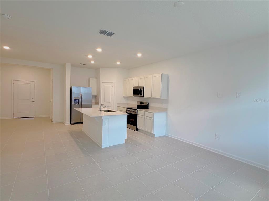 A kitchen with white cabinets, stainless steel appliances, and a central island on tiled flooring — 618 POPPY LANE, DUNDEE, FL