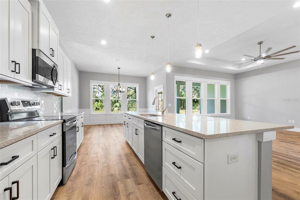 A modern kitchen features white cabinets, stainless steel appliances, and a large granite-topped island — 0 SW KIMBERLY LANE LOT 6 DRIVE, LAKE CITY, FL
