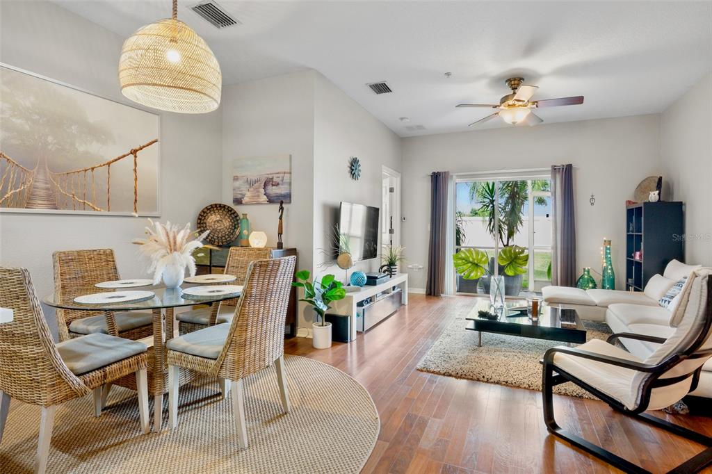 A living and dining area features wood floors, a glass-top table, and a white sofa — 3537 PARKRIDGE CIRCLE UNIT 15-106, SARASOTA, FL