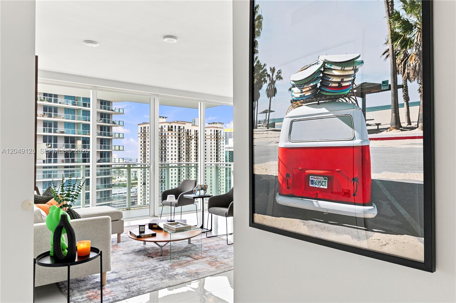 A living room with a large framed surf van print, modern furniture, and floor-to-ceiling windows — 1080 Brickell Ave # 2609, Miami FL 33131, MIAMI, FL
