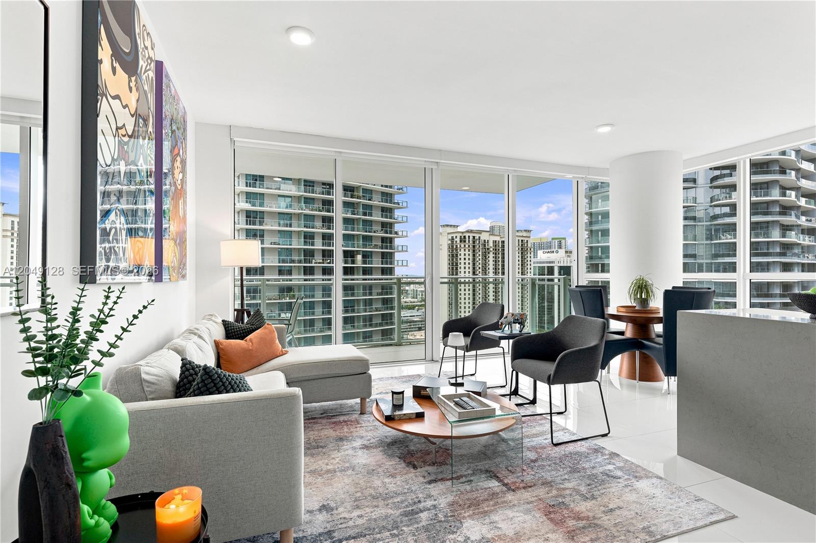 A modern living room features a sectional sofa, a round coffee table, and floor-to-ceiling windows — 1080 Brickell Ave # 2609, Miami FL 33131, MIAMI, FL