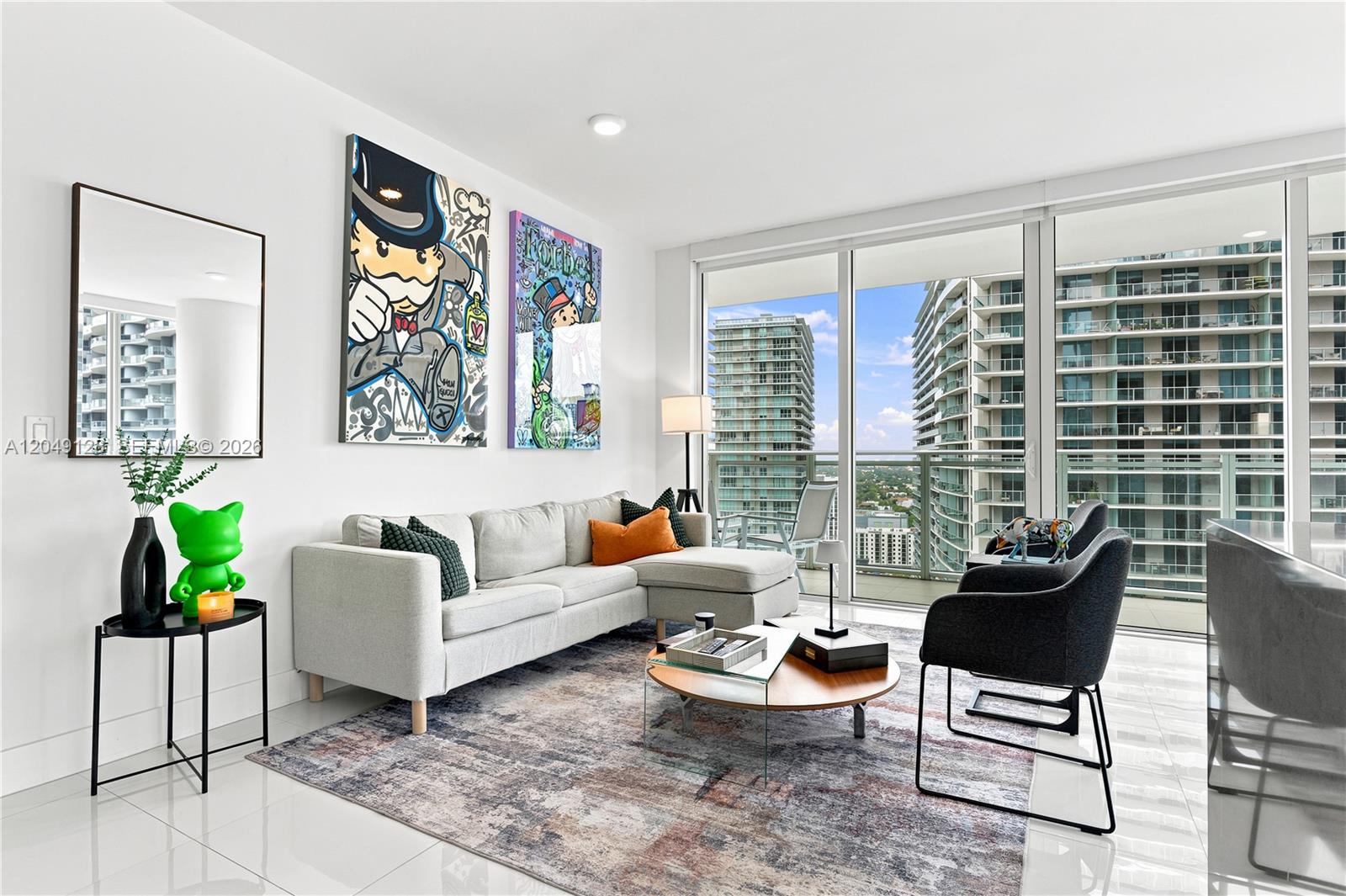 A modern living room features a sectional sofa, pop art, and floor-to-ceiling windows with city views — 1080 Brickell Ave # 2609, Miami FL 33131, MIAMI, FL