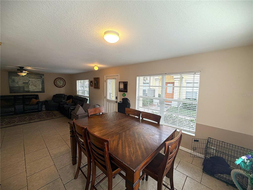 A dining area with a wooden table and chairs sits in front of a living room — 3858 ISLAND WAY, ST PETERSBURG, FL