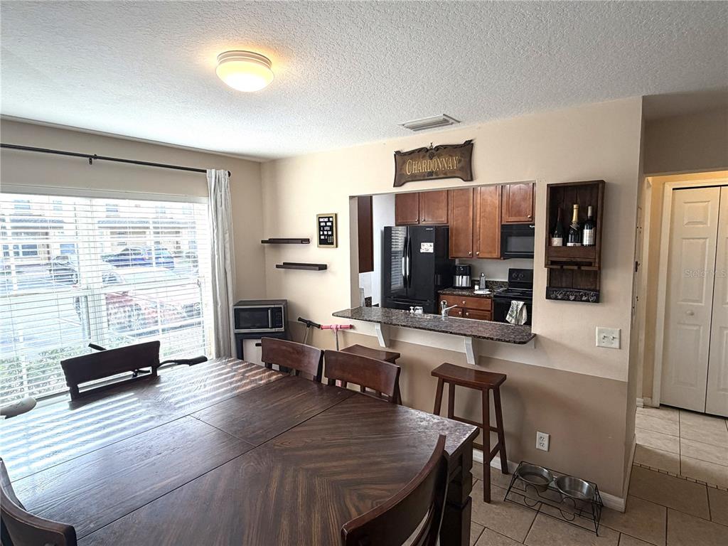 A dining area with a wooden table, bar seating, and an open kitchen pass-through window — 3858 ISLAND WAY, ST PETERSBURG, FL