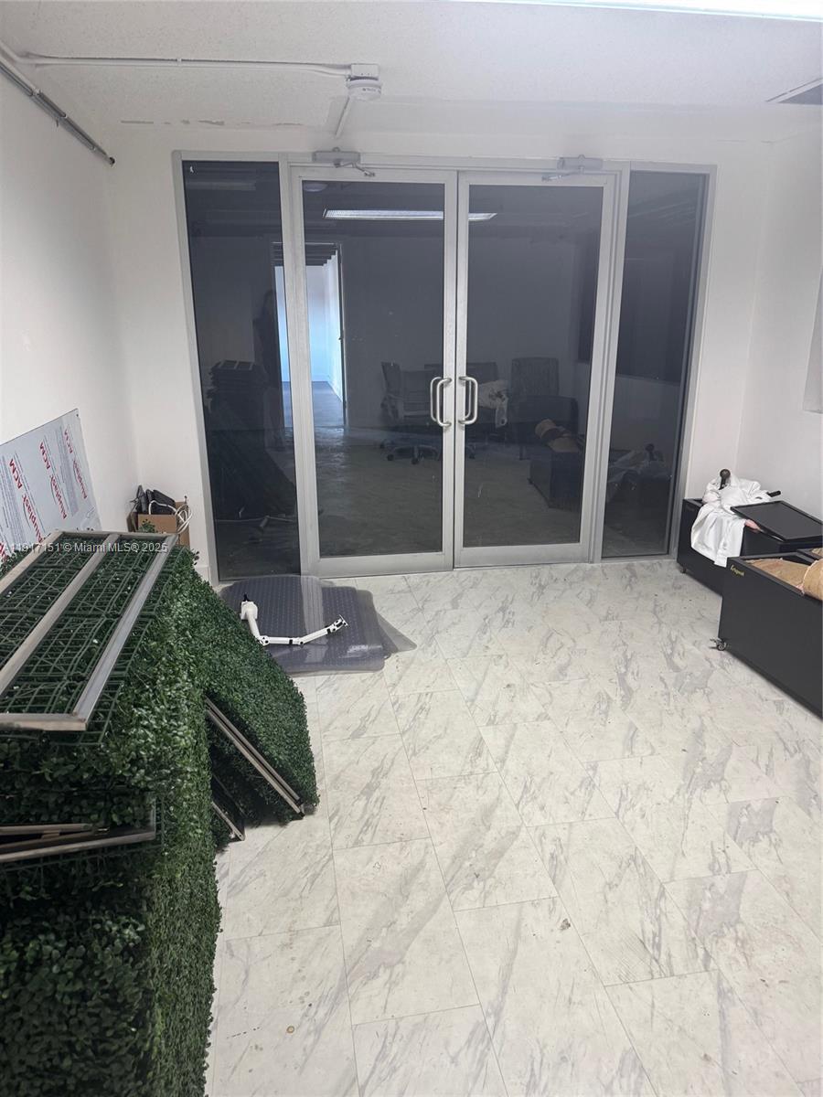 An office room features marble-look tile flooring, glass double doors, and scattered furniture and equipment — 4751 W Flagler St, Miami FL 33134, MIAMI, FL