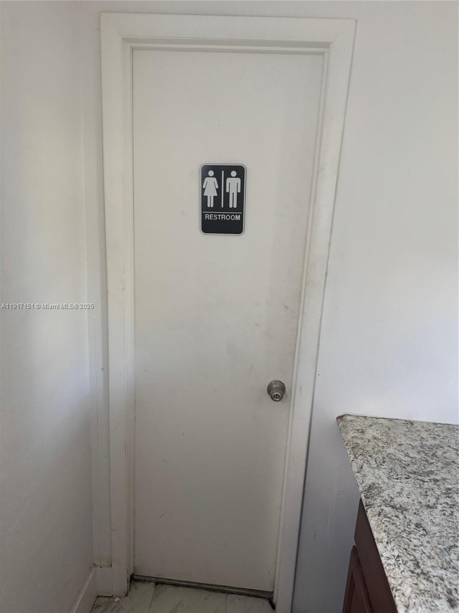A white door with a restroom sign is situated next to a granite countertop — 4751 W Flagler St, Miami FL 33134, MIAMI, FL