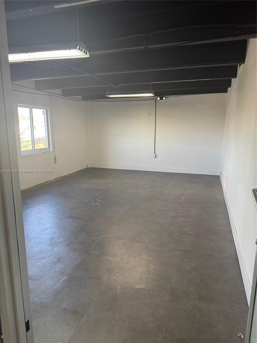 An empty room features gray tile flooring, white walls, and an exposed black ceiling — 4751 W Flagler St, Miami FL 33134, MIAMI, FL
