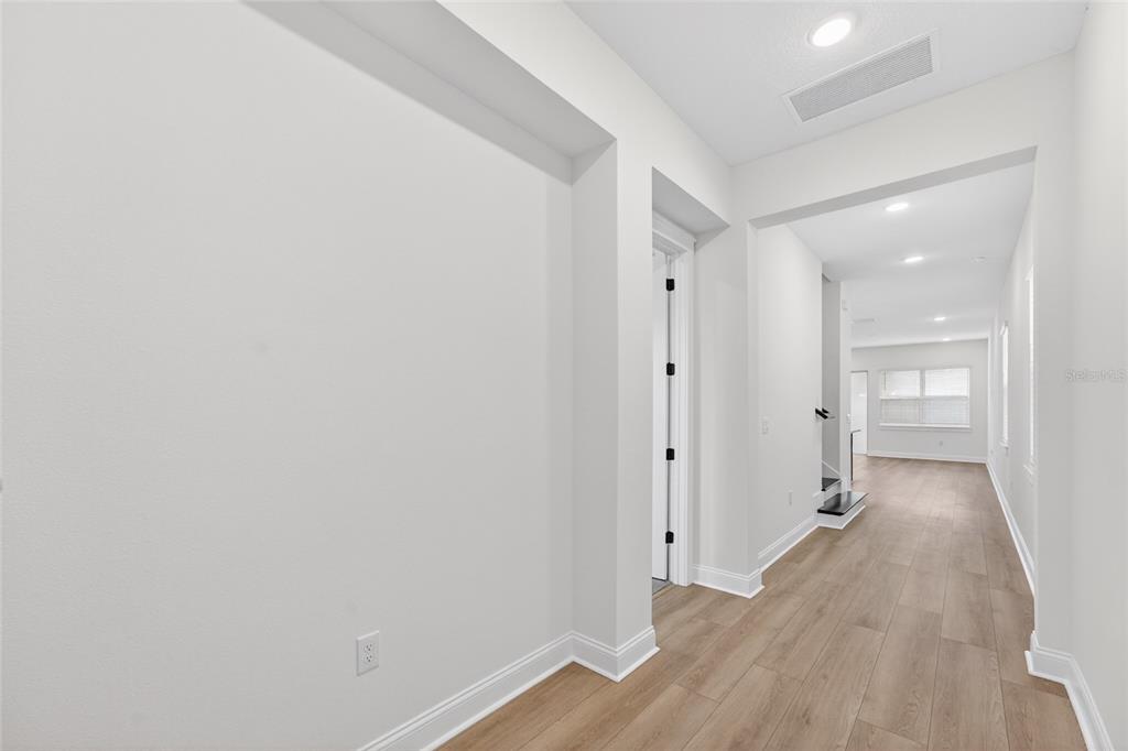 A bright hallway with light wood flooring leads toward an open living area — 15174 FIELD DAISY DRIVE, WINTER GARDEN, FL