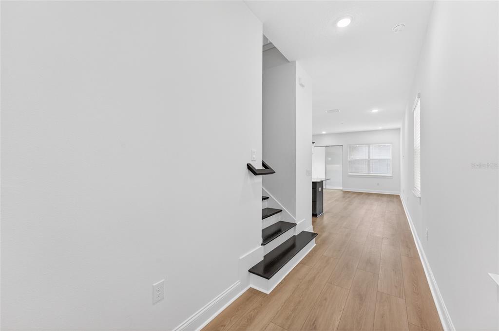 A staircase with dark wood treads leads upward next to a hallway with light flooring — 15174 FIELD DAISY DRIVE, WINTER GARDEN, FL