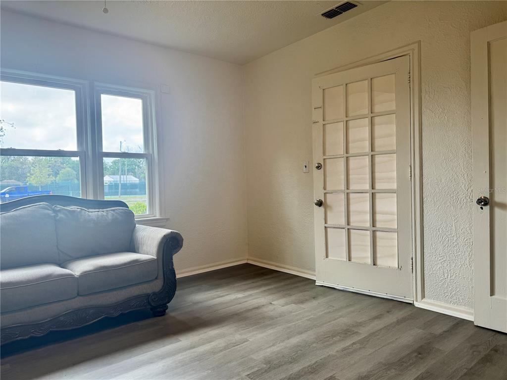A living room features gray wood-look flooring, a beige sofa, and a white French door — 425 E SESSOMS AVENUE, LAKE WALES, FL