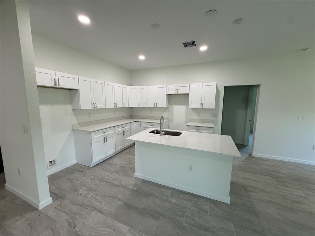 A kitchen features white cabinets, light countertops, a center island with a sink, and tile flooring — 2669 MAXIMO ROAD, NORTH PORT, FL