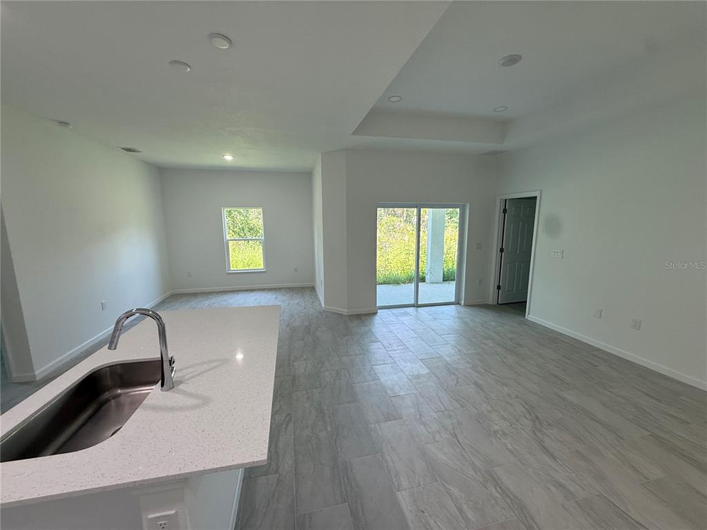 A kitchen island with a sink overlooks an open-concept living area with tile flooring — 2669 MAXIMO ROAD, NORTH PORT, FL