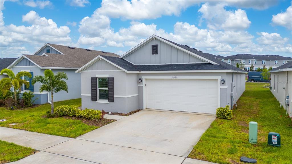 A single-story gray house with a two-car garage and a concrete driveway — 9061 OSCRAFT DRIVE, DAVENPORT, FL