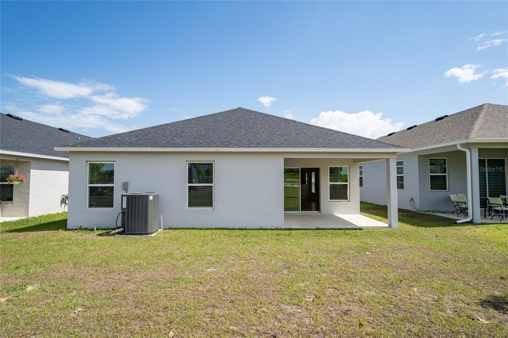 The rear exterior of a single-story house features a covered patio and an HVAC unit — 9061 OSCRAFT DRIVE, DAVENPORT, FL