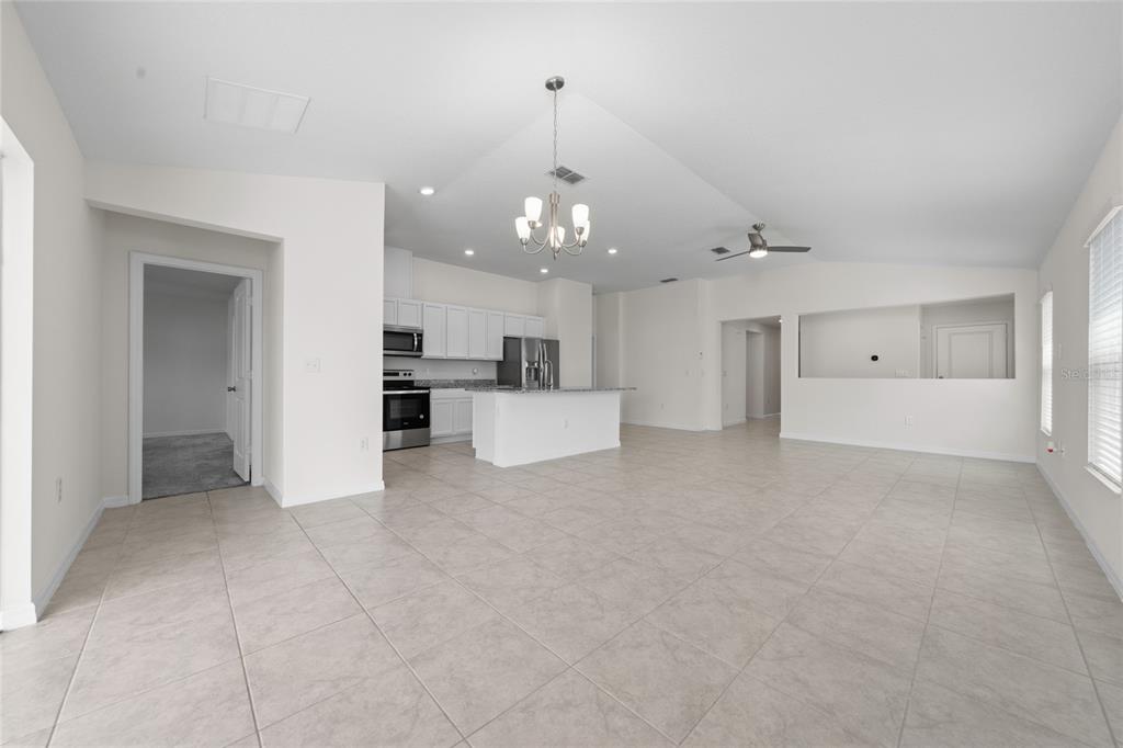 An open-concept kitchen and living area with white cabinets, a central island, and tile flooring — 9061 OSCRAFT DRIVE, DAVENPORT, FL