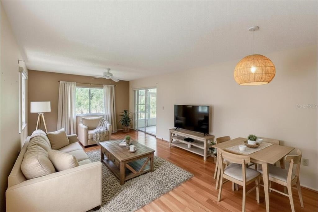 A living and dining area with hardwood floors, a beige sofa, and a woven pendant light — 6419 REMUS DRIVE, NEW PORT RICHEY, FL