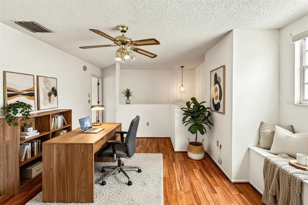 A home office with a wooden desk, bookshelf, ceiling fan, and a window seat — 6419 REMUS DRIVE, NEW PORT RICHEY, FL