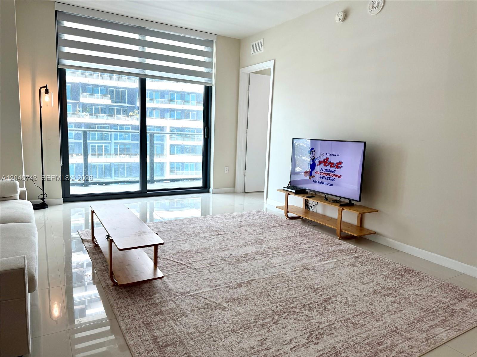 A living room features white tile floors, a large area rug, and a sliding glass door — 1300 S Miami Ave # 4108, Miami FL 33130, MIAMI, FL