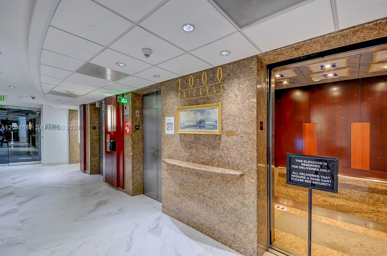 An elevator lobby features marble floors, granite walls, and a framed painting between elevator doors — 1000 Brickell Ave # 7F, Miami FL 33131, MIAMI, FL