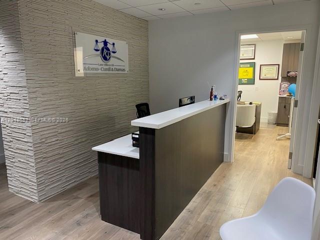 A reception area features a dark wood desk, a textured stone wall, and light wood flooring — 1000 Brickell Ave # 7F, Miami FL 33131, MIAMI, FL