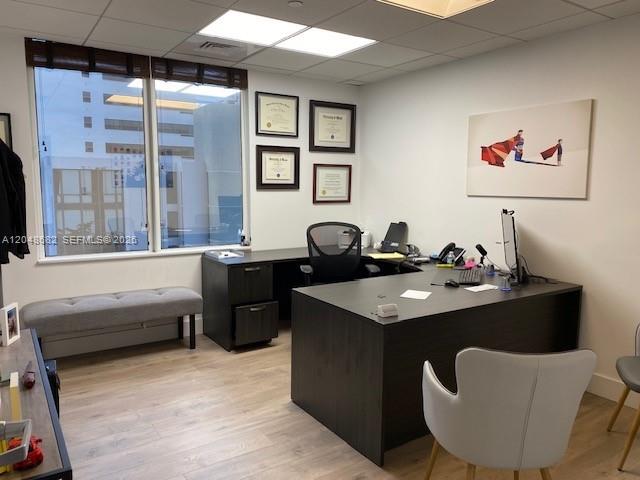 A modern office features a dark wood desk, a gray bench, and framed wall art — 1000 Brickell Ave # 7F, Miami FL 33131, MIAMI, FL