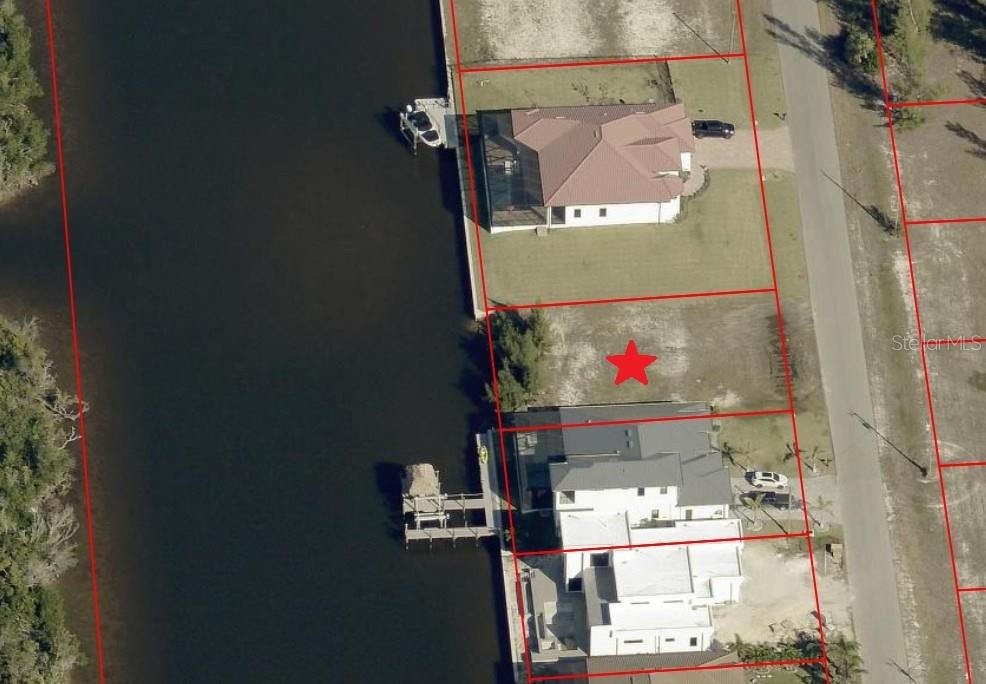 This aerial view shows a vacant waterfront lot marked with a red star — 3002 NW 47TH AVENUE, CAPE CORAL, FL