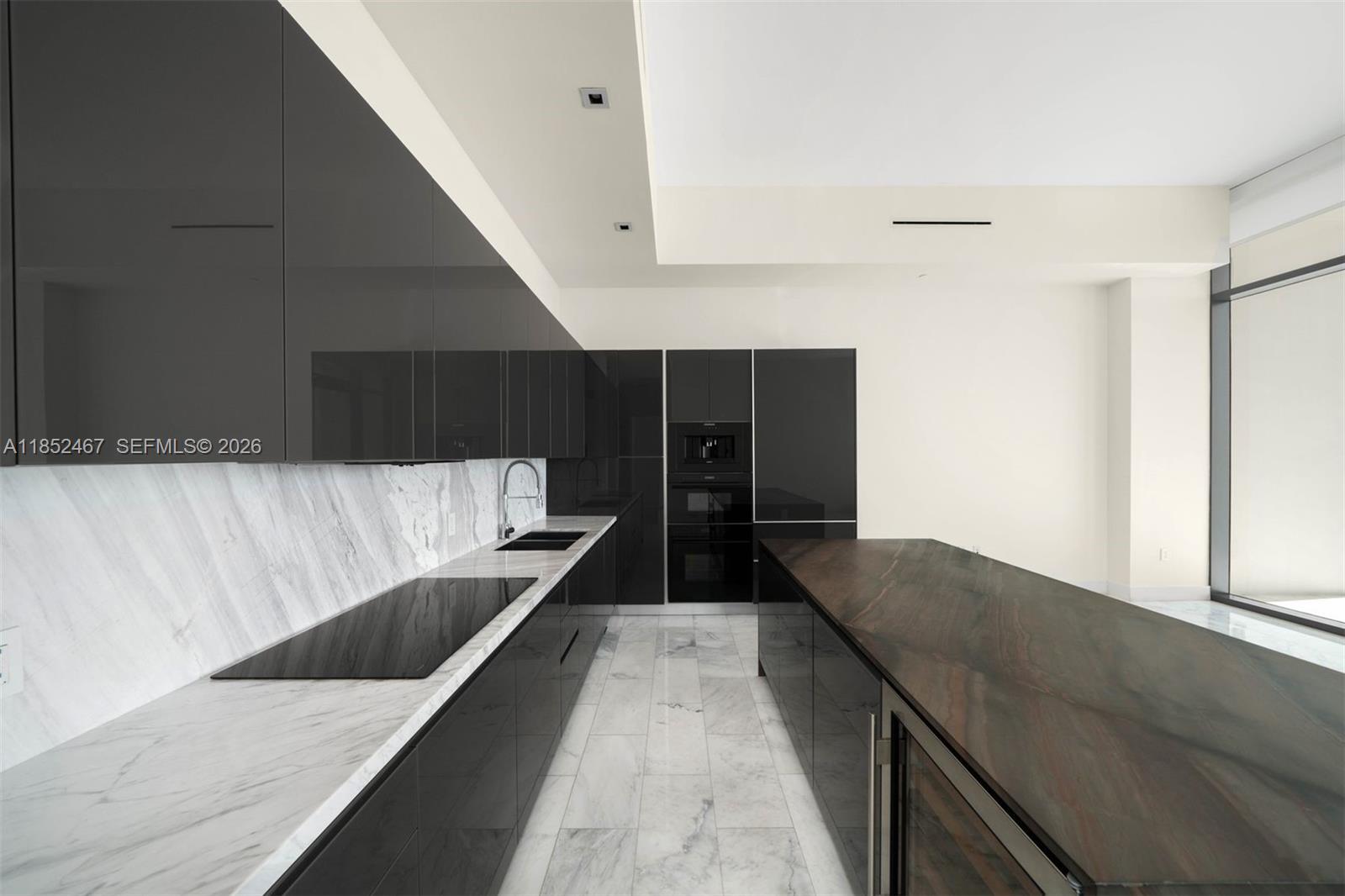 A modern kitchen features dark glossy cabinets, a marble backsplash, and a large stone island — 1451 Brickell Ave # 5302, Miami FL 33131, MIAMI, FL