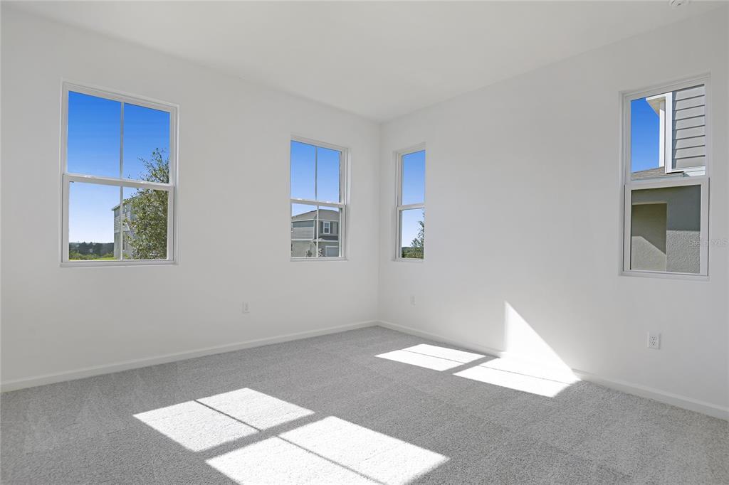 An empty bedroom features white walls, gray carpeting, and four windows with exterior views — 1257 DAISY HILL AVENUE, DUNDEE, FL