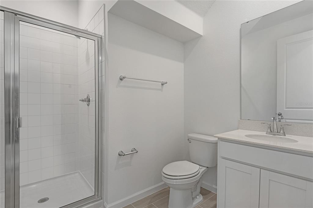 A bathroom features a glass-enclosed shower, a white vanity with a sink, and a toilet — 1257 DAISY HILL AVENUE, DUNDEE, FL