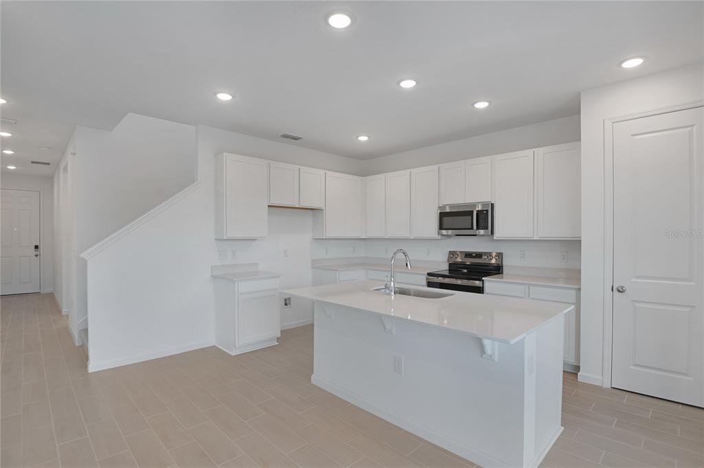 A modern kitchen features white cabinets, a central island, and light-colored tile flooring — 1257 DAISY HILL AVENUE, DUNDEE, FL