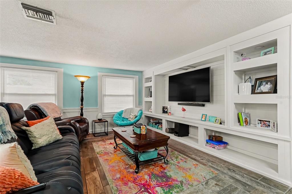 A living room features a large built-in media center, a colorful rug, and light blue walls — 4315 STRATFIELD DRIVE, NEW PORT RICHEY, FL