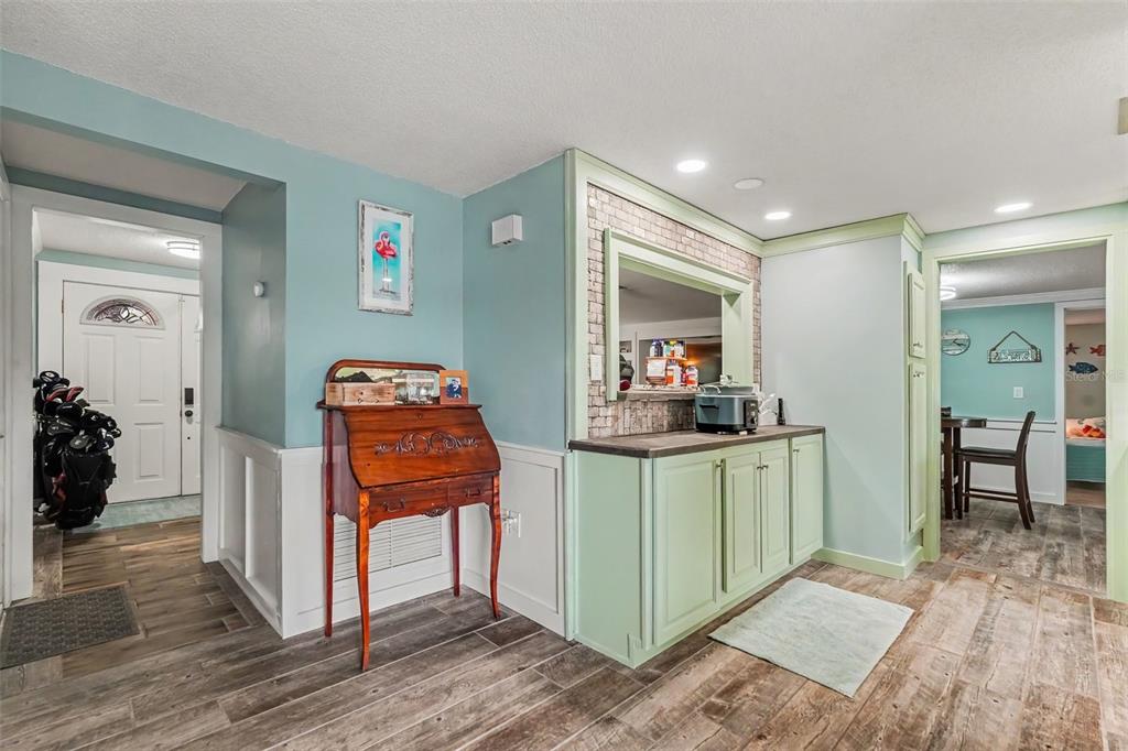 A room with light blue walls, wood-look tile floors, a green cabinet, and a wooden desk — 4315 STRATFIELD DRIVE, NEW PORT RICHEY, FL