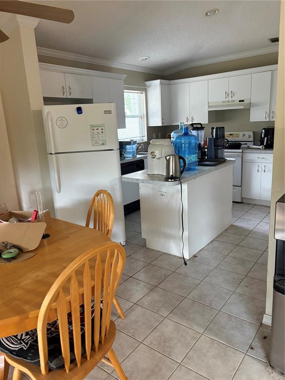 A kitchen features white cabinetry, a white refrigerator, a central island, and tile flooring — 3743 WAKE AVENUE, SARASOTA, FL