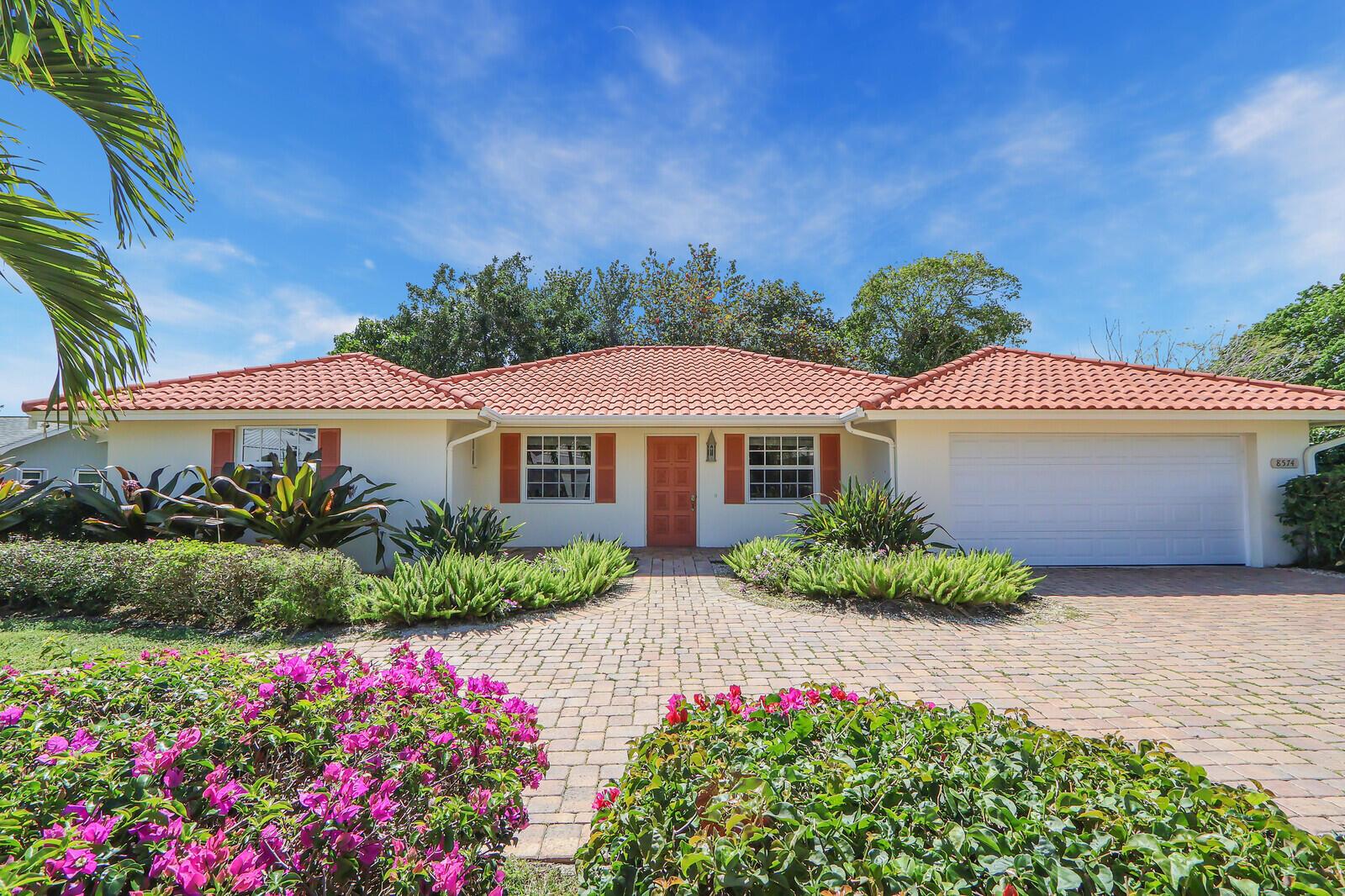 A single-story house with a terracotta tile roof, white stucco walls, and a brick driveway — 8574 SE Seagrape Way, Hobe Sound FL 33455, HOBE SOUND, FL