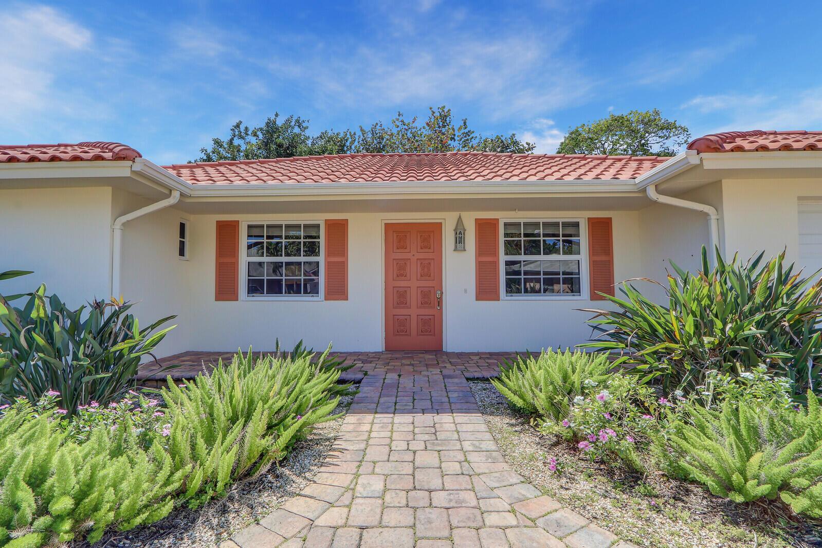 A single-story house with a terracotta tile roof, orange shutters, and a brick walkway — 8574 SE Seagrape Way, Hobe Sound FL 33455, HOBE SOUND, FL