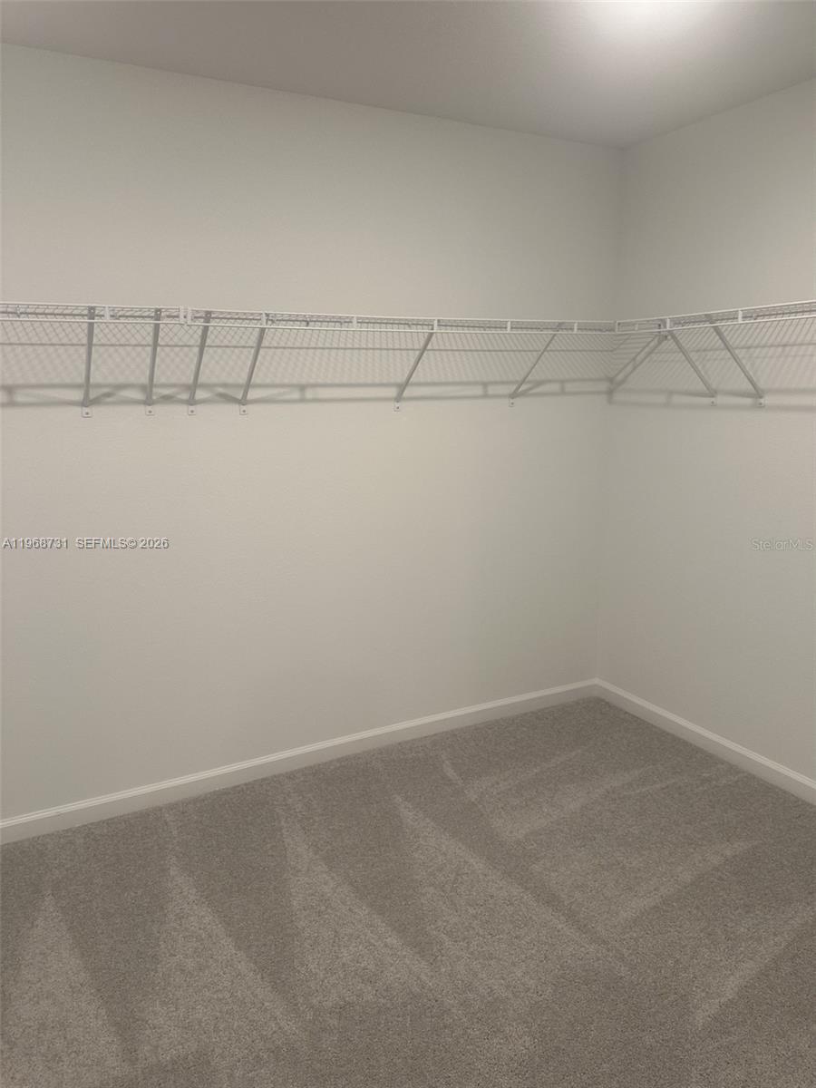 A walk-in closet features white wire shelving and light-colored carpeting — 13110 SW 89TH ST, Ocala FL 34432, OCALA, FL