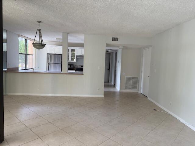 An open-concept living area features light-colored tile flooring, a kitchen with white cabinets, and hallways — 500 Egret Circle # 8211, Delray Beach FL 33444, DELRAY BEACH, FL
