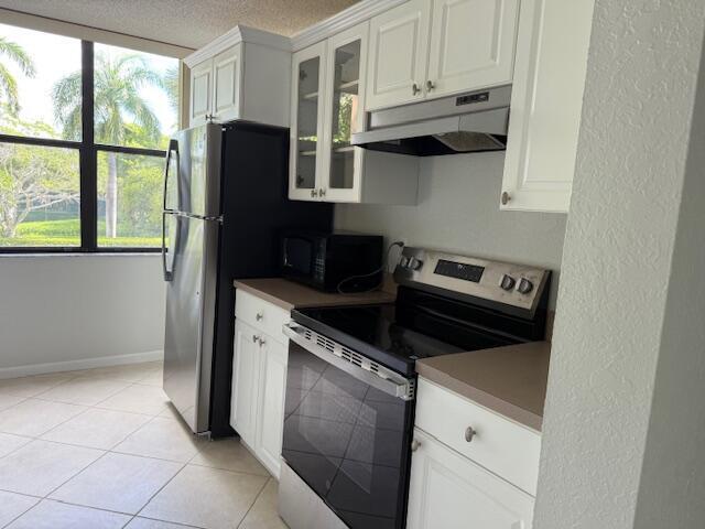 A kitchen features white cabinets, stainless steel appliances, and a window overlooking palm trees — 500 Egret Circle # 8211, Delray Beach FL 33444, DELRAY BEACH, FL