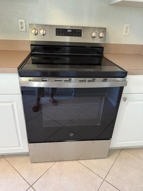 A stainless steel GE electric range is centered between white cabinets and tan countertops — 500 Egret Circle # 8211, Delray Beach FL 33444, DELRAY BEACH, FL