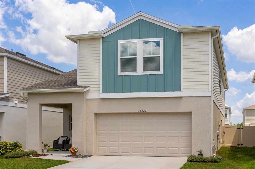 A two-story house with a beige stucco lower level, teal vertical siding, and a garage — 34327 VERBENA STREET, WESLEY CHAPEL, FL
