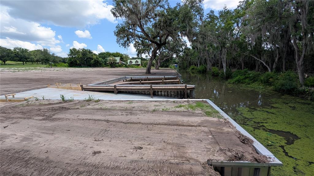 A wooden dock extends into a canal next to a cleared, sandy lot with trees — SULEN ROAD, LADY LAKE, FL