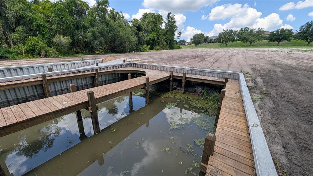 A wooden boat slip and dock sit adjacent to a large, cleared dirt lot — SULEN ROAD, LADY LAKE, FL