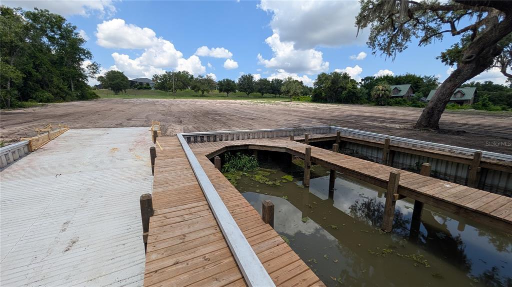 A wooden boat dock extends into a small canal next to a cleared, grassy lot — SULEN ROAD, LADY LAKE, FL