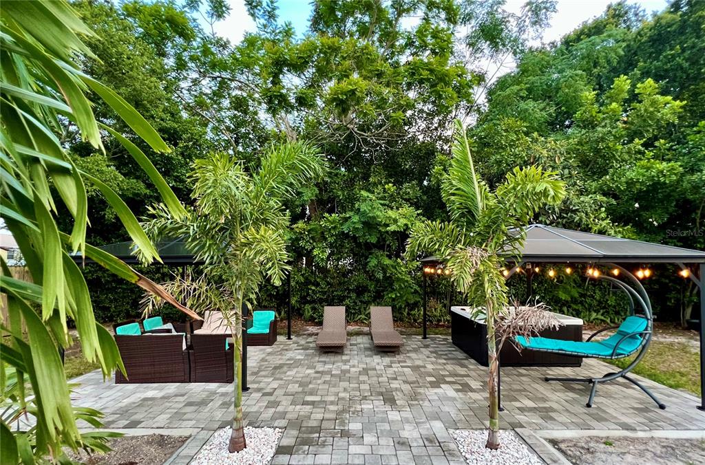 A paved patio features two gazebos, lounge chairs, a hot tub, and two palm trees — 1237 LOTUS PATH, CLEARWATER, FL