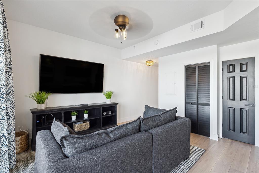 A living room features a dark gray sofa, a television, and a black media console — 8800 BAY PINES BOULEVARD UNIT 102, ST PETERSBURG, FL