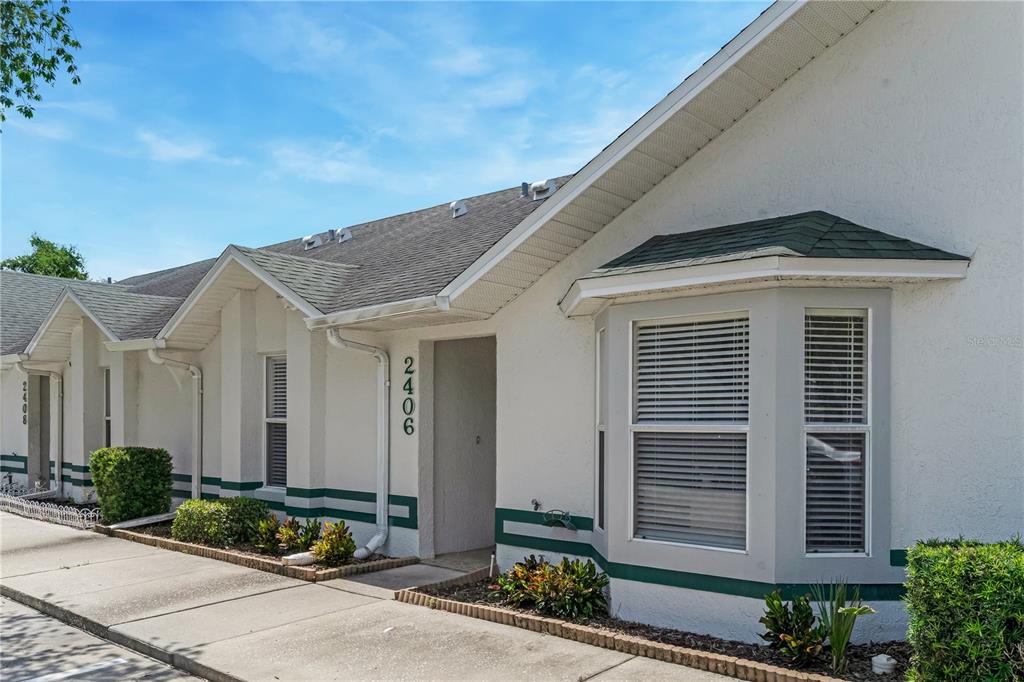 A white exterior of a residential building with a bay window and green trim — 2406 KAM COURT, KISSIMMEE, FL