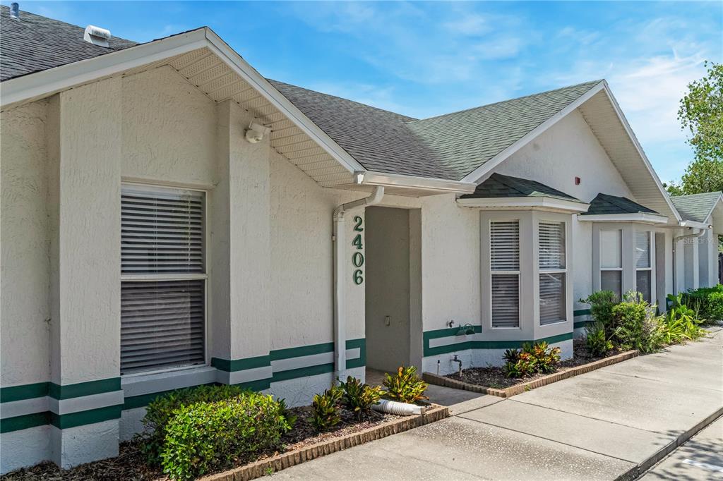 A single-story building exterior features white stucco walls, green trim, and a shingled roof — 2406 KAM COURT, KISSIMMEE, FL