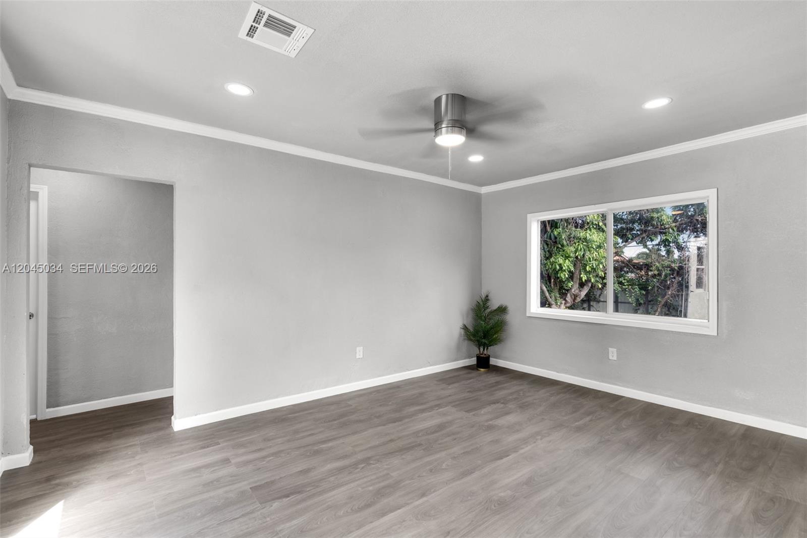 An empty room features gray walls, wood-look flooring, a ceiling fan, and a window — 1246 Fisherman St, Opa-Locka FL 33054, OPA-LOCKA, FL