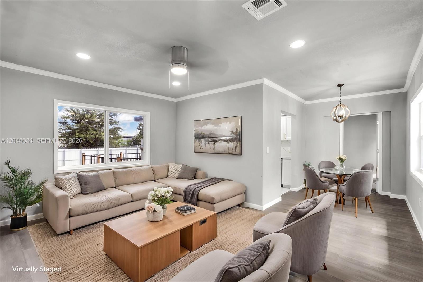 This living and dining area features light gray walls, wood-look flooring, and neutral furniture — 1246 Fisherman St, Opa-Locka FL 33054, OPA-LOCKA, FL