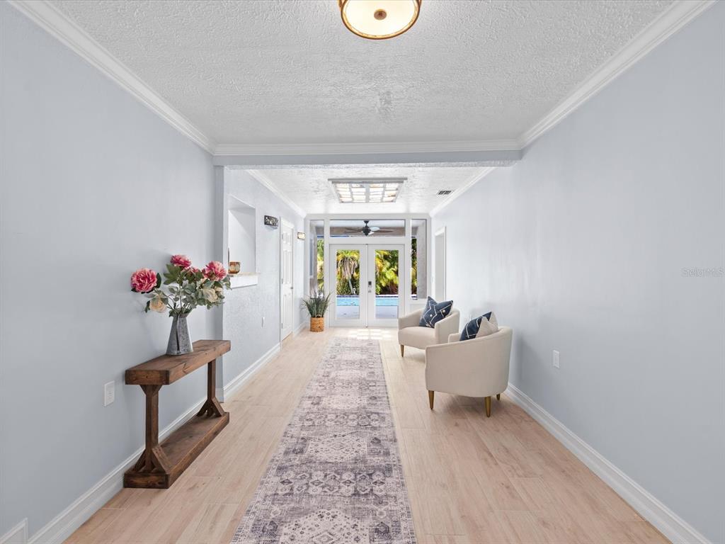 A bright hallway features light wood-look flooring, a long patterned runner, and double glass doors — 502 FLORIDA BOULEVARD, CRYSTAL BEACH, FL